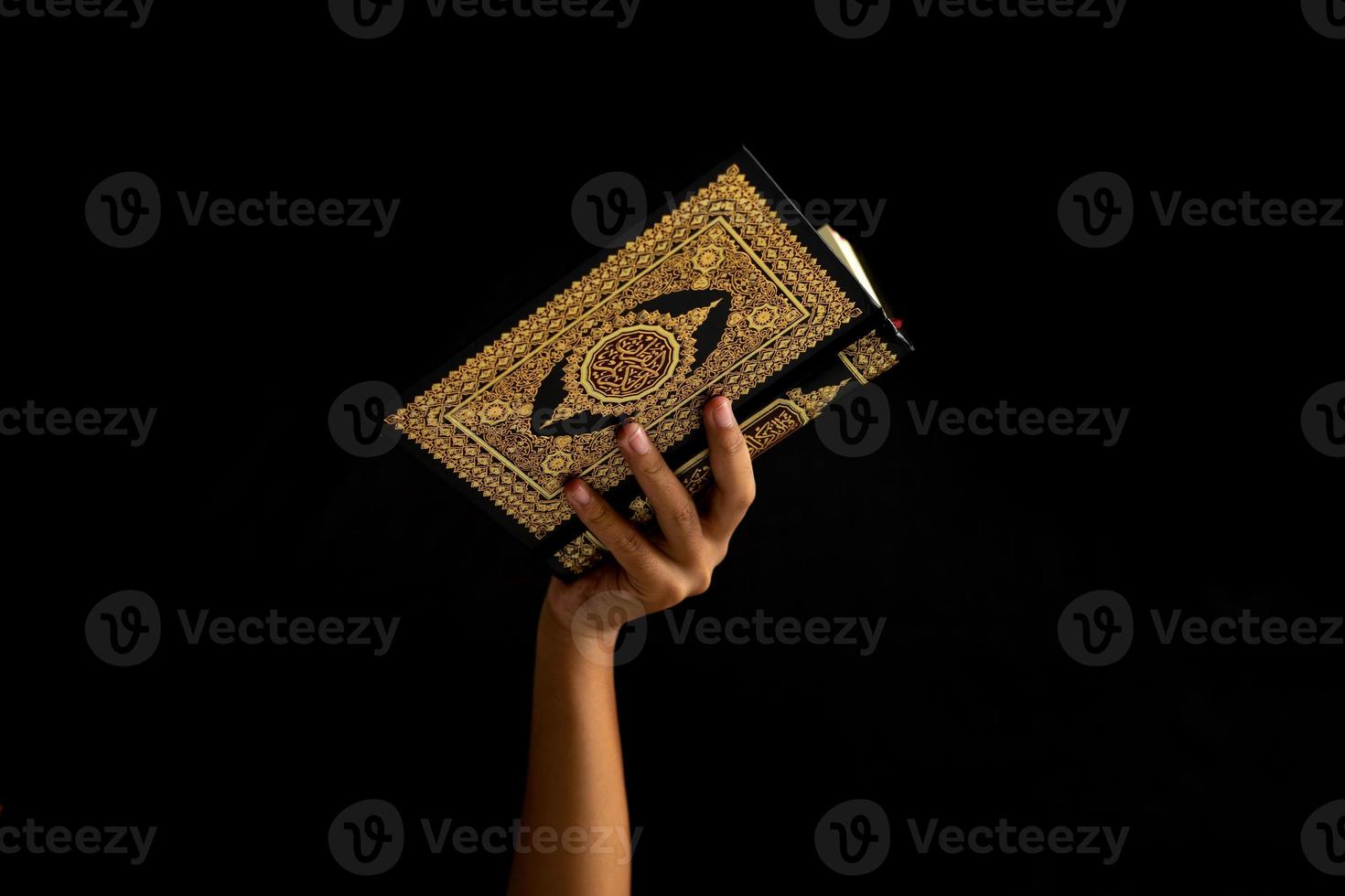 Hands holding holy Quran in black background photo