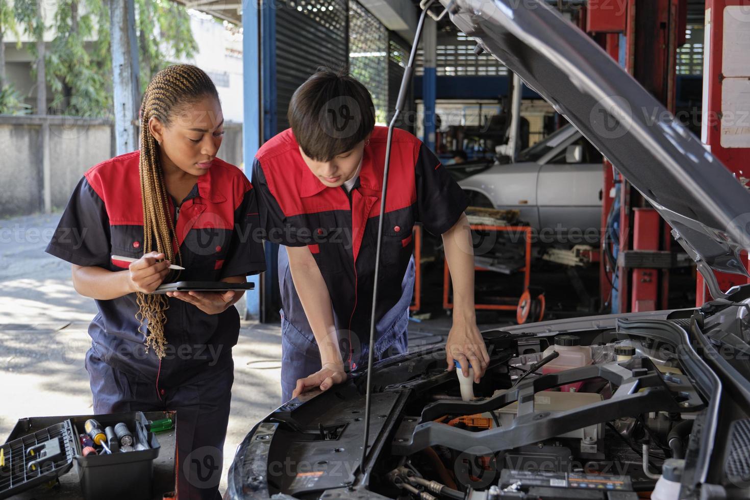 Two professional automotive mechanical partners check and repair an EV car battery and hybrid engine at a maintenance garage, expert electric vehicle service, and fixing occupations auto industry. photo