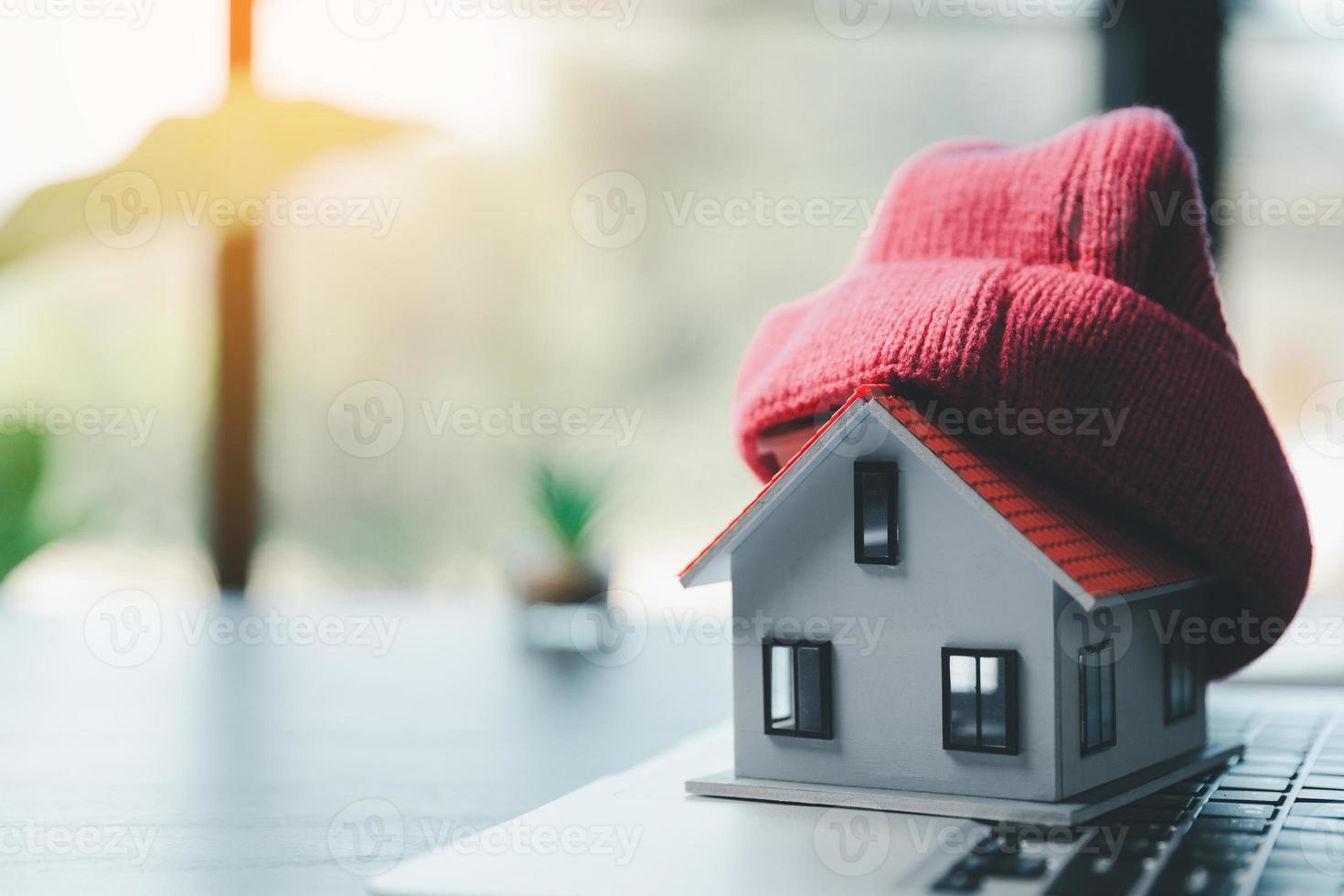 Close up conceptual of insulation symbol house with red bonnet in office bureau. insurance protective hand over house for protection and care, Concept of home and real estate Property insurance. photo