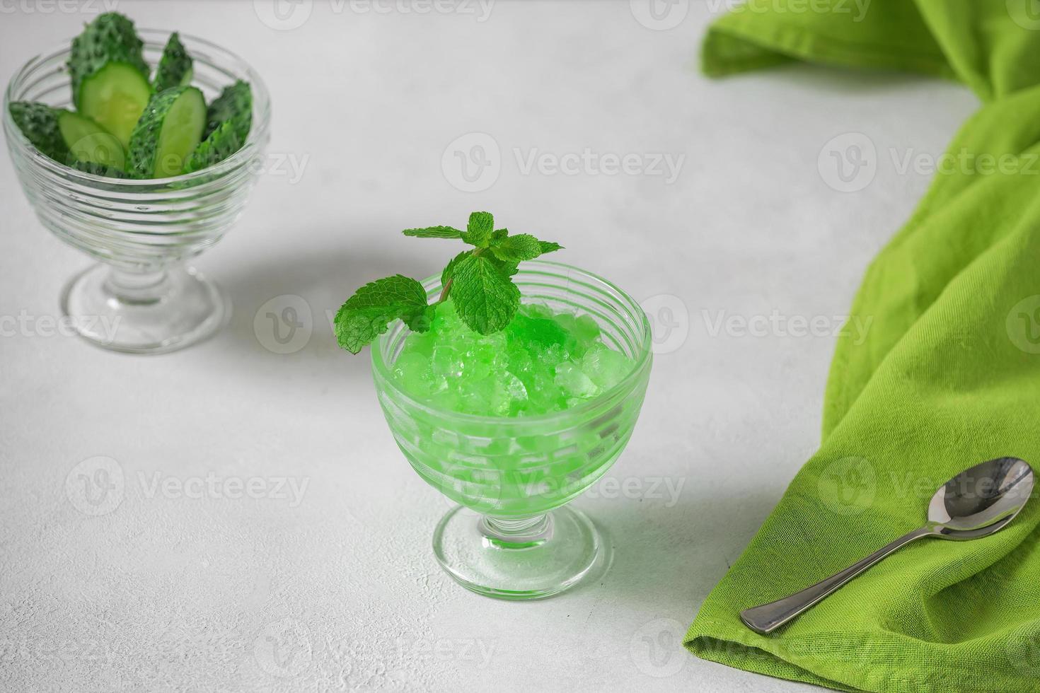 Summer Sicilian dessert granita, frozen juice of fresh cucumber and mint on a white background. Summer cooling, tonic cocktail of crushed ice, a kind of sherbet. photo