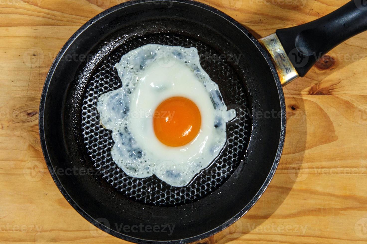 Cooking roasted eggs for breakfast, another egg is driven into pan for fried eggs. photo