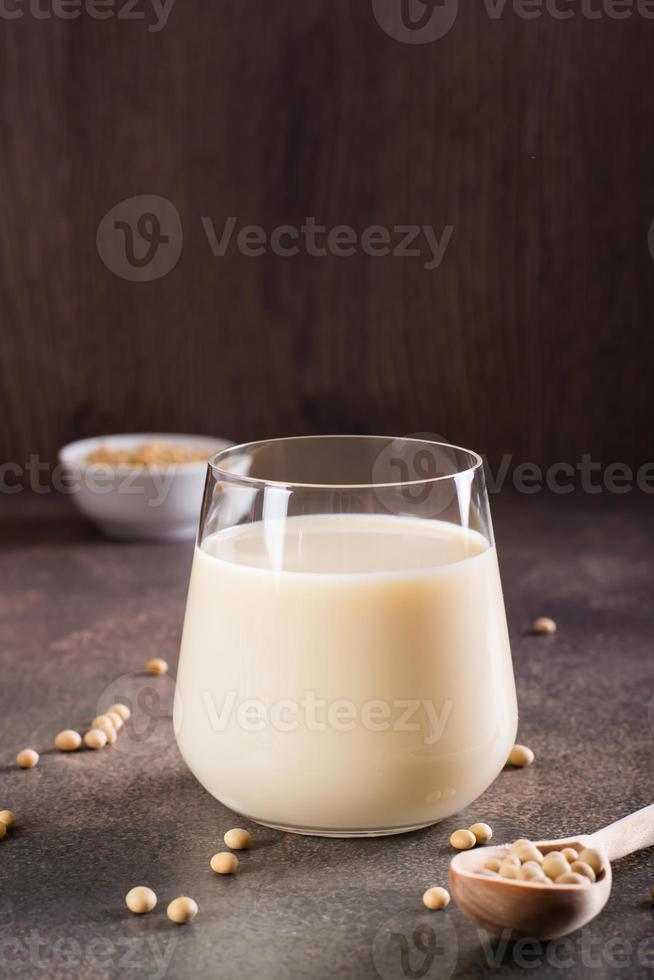 soja Leche en un vaso y soja en un cuenco en el mesa. lactosa gratis beber. vertical ver foto