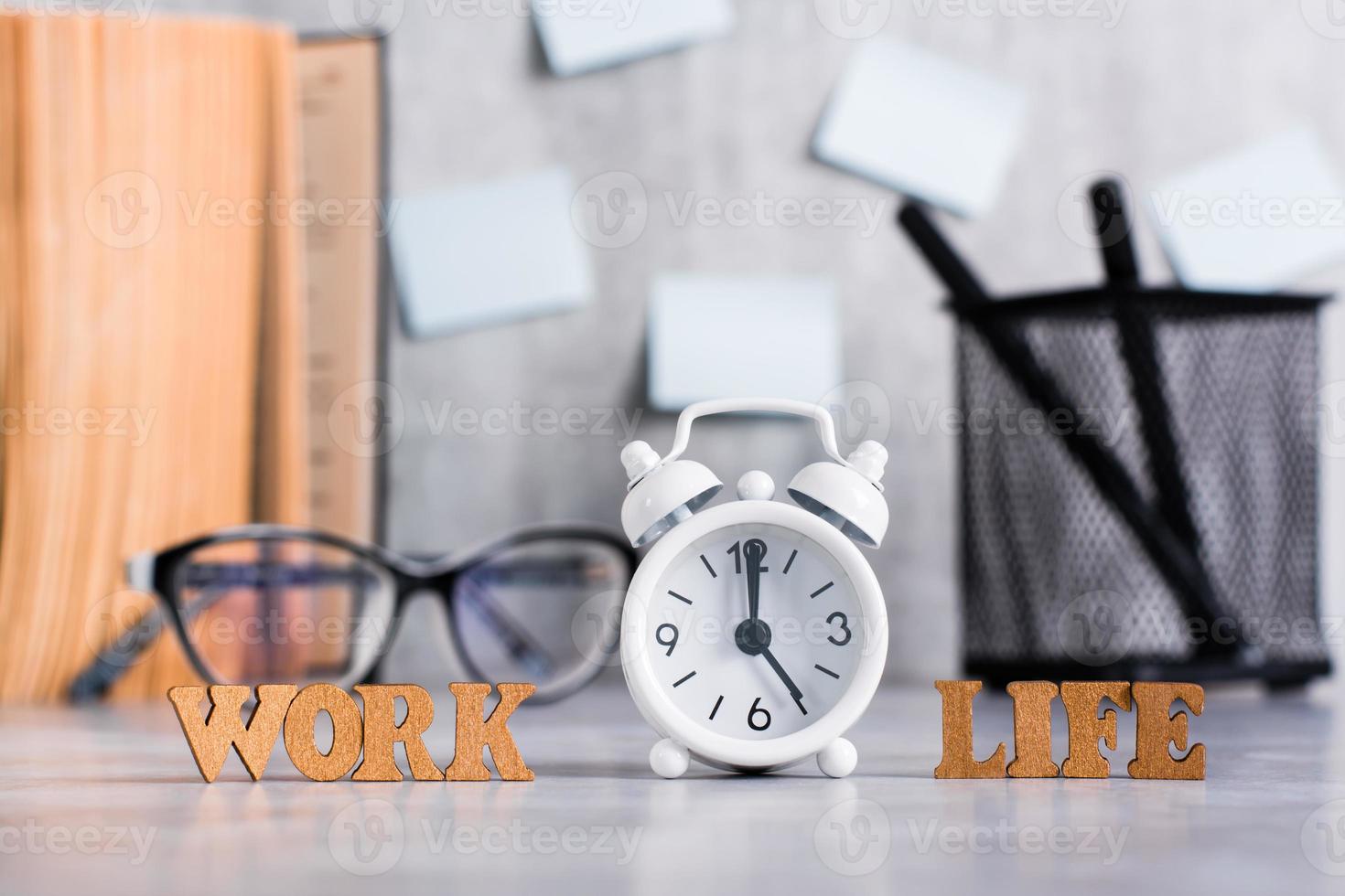 Work life balance concept. Wooden letters and an alarm clock on the desktop. photo