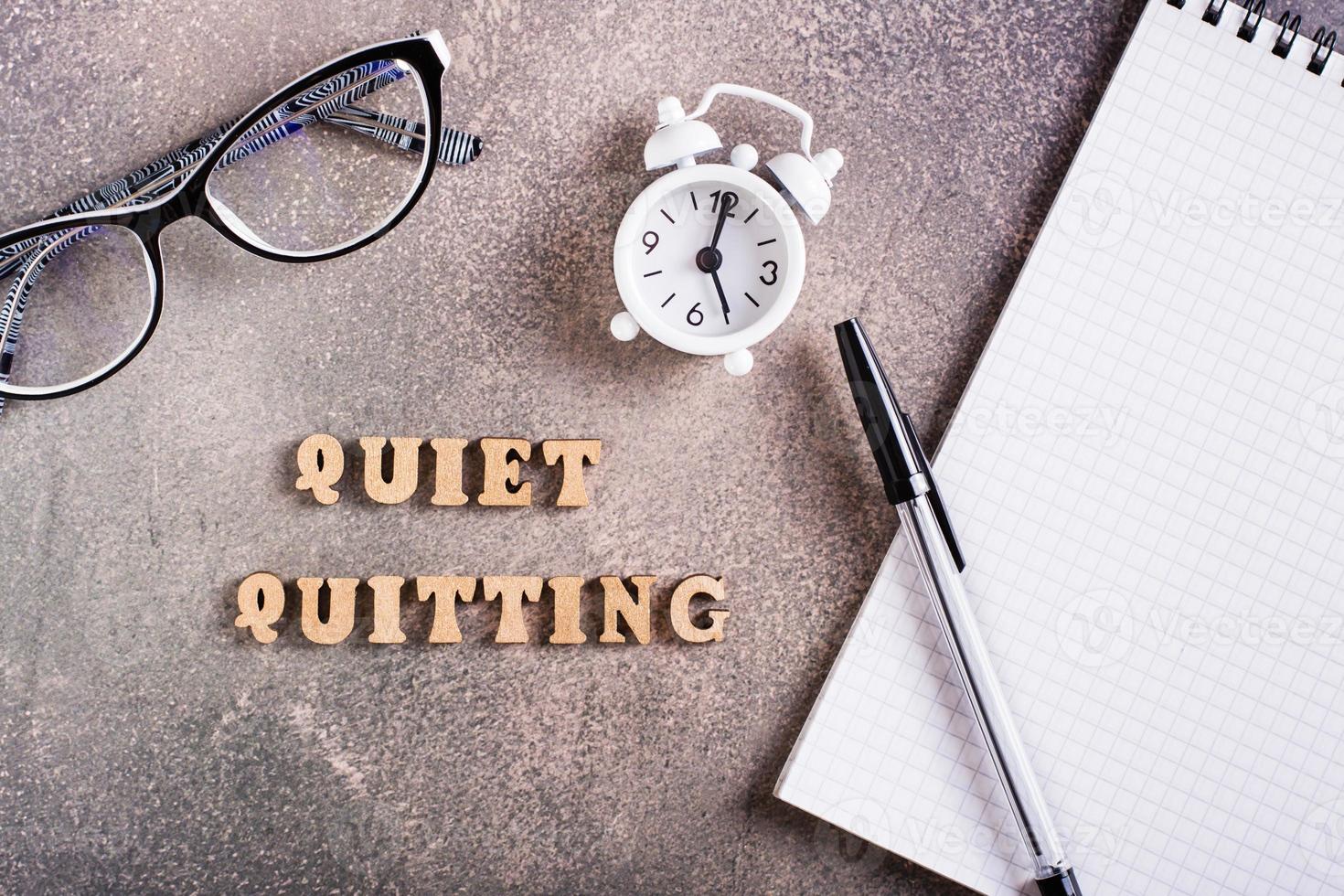 Quiet quitting concept. Wooden letters, stationery and alarm clock. Top