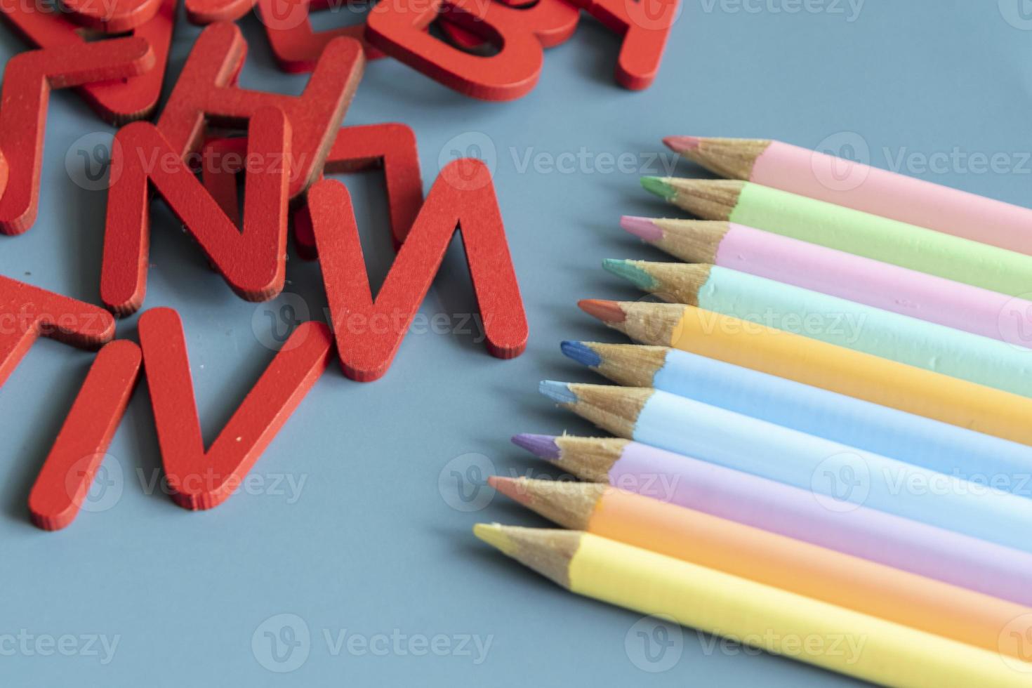 Back to school concept with assorted letters and colored pencils in pastel colors photo