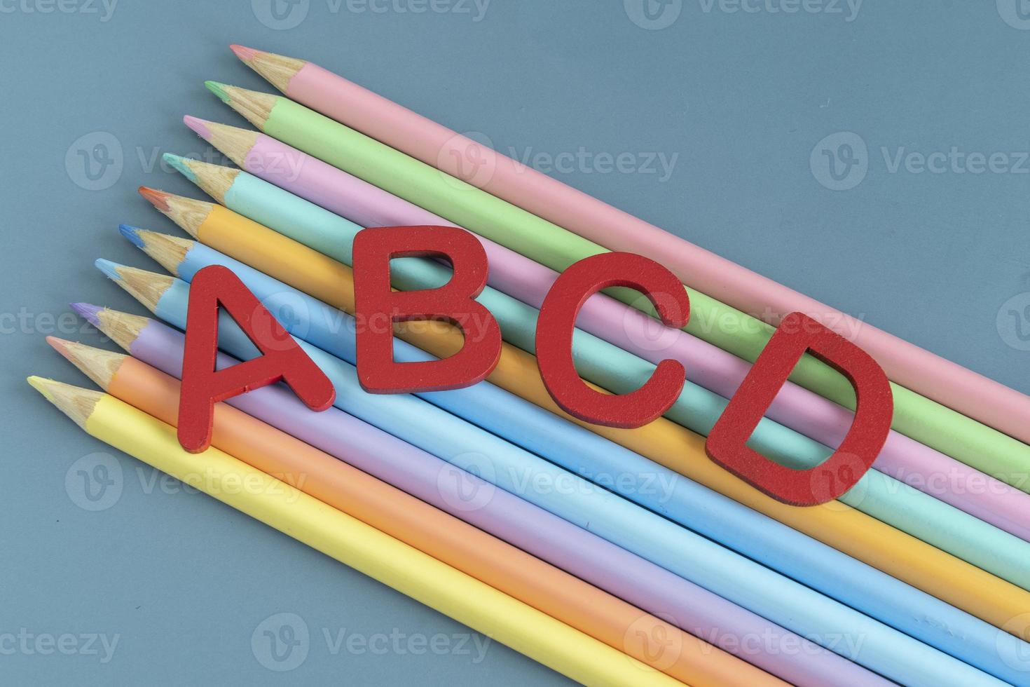 Back to school concept with assorted letters and colored pencils in pastel colors photo
