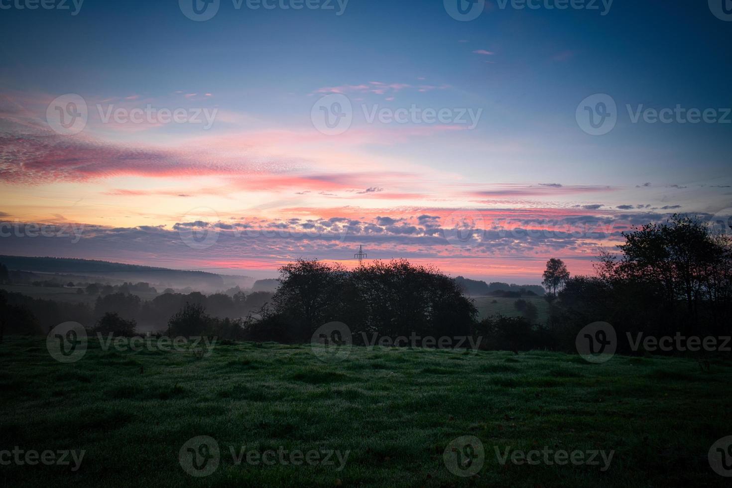 Sunrise over a neighboring forest with meadow in the foreground. Pasture landscape photo