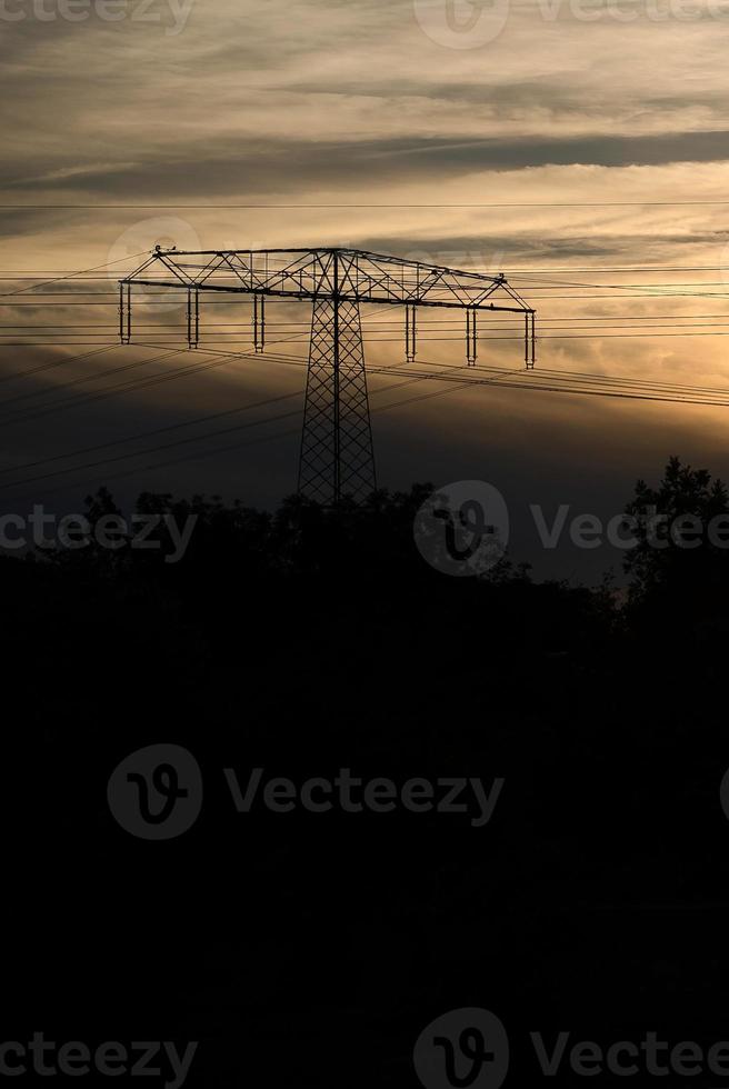 High-voltage power pole with overhead line through which the electricity is transported photo