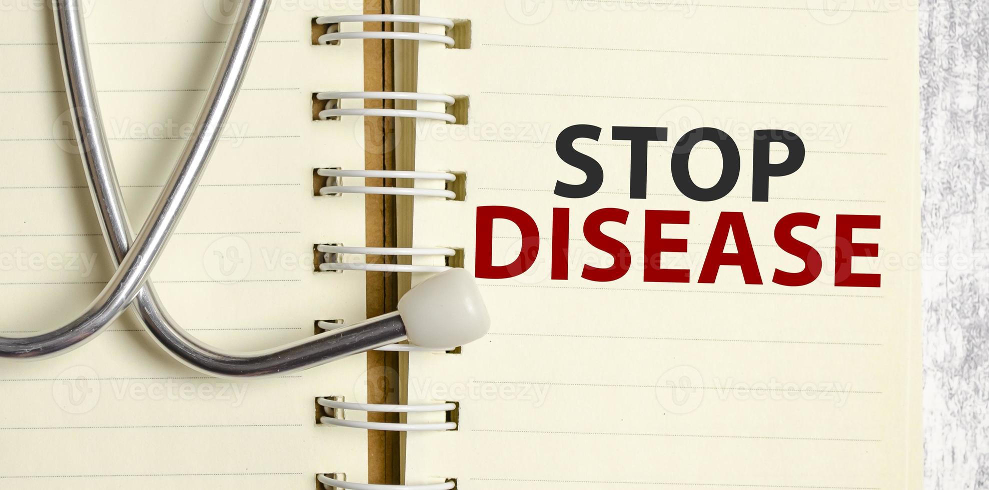 Stethoscope and notebook with stop disease text on notebook photo