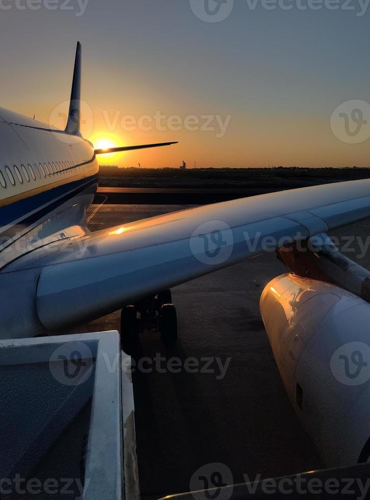 vertical imagen, silueta de un pasajero avión aterrizaje en el aeropuerto delantal en contra el fondo de el pintoresco naranja puesta de sol cielo foto