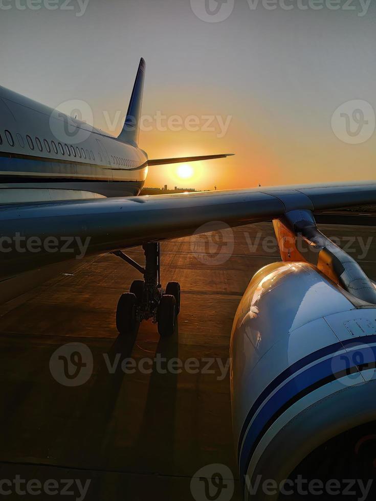 vertical imagen, silueta de un pasajero avión aterrizaje en el aeropuerto delantal en contra el fondo de el pintoresco naranja puesta de sol cielo foto