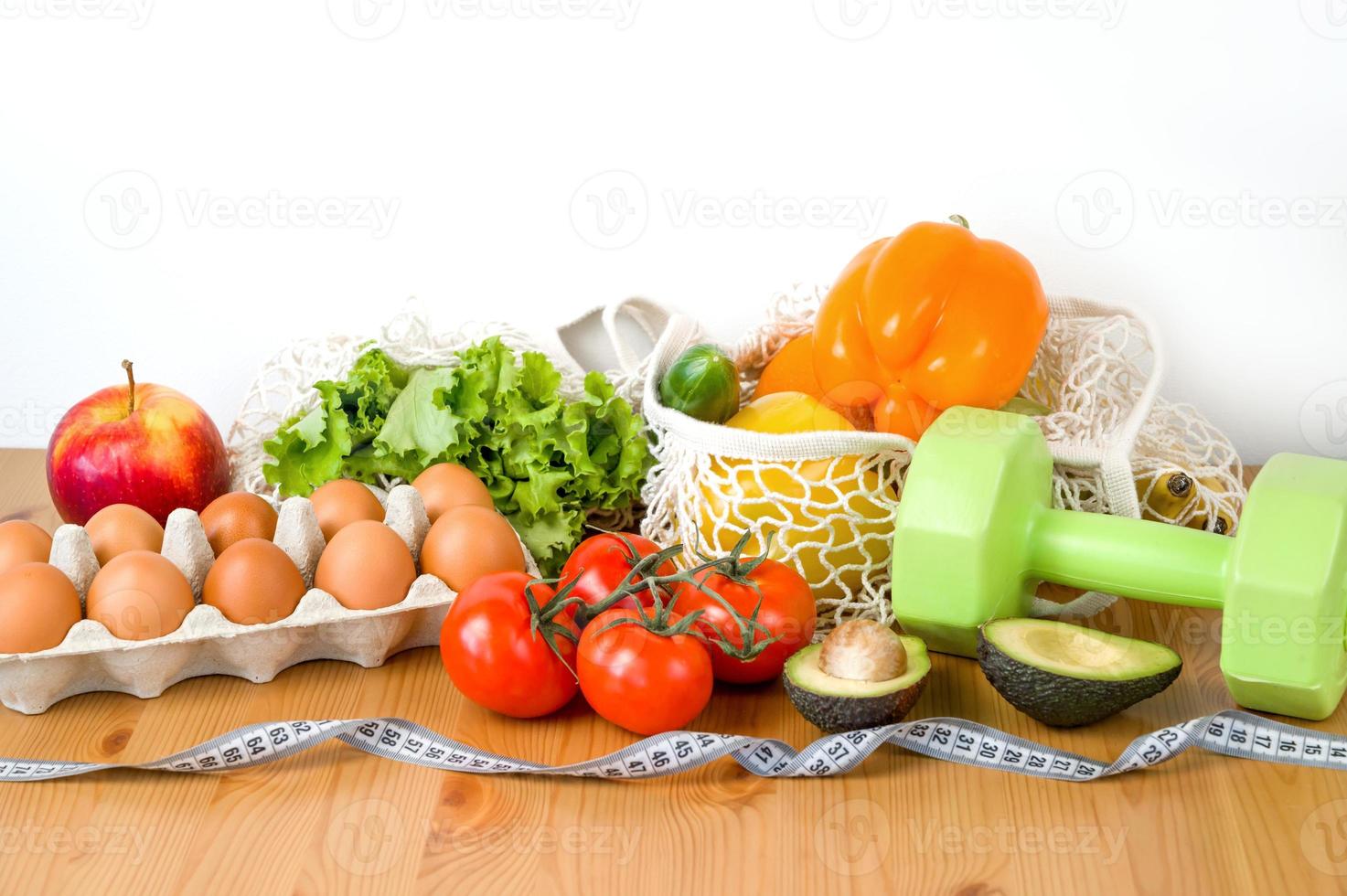 Vegetables,fruit and eggs near dumbbells and measuring tape. Sport and diet cocnept. HEalthy lifestyle photo