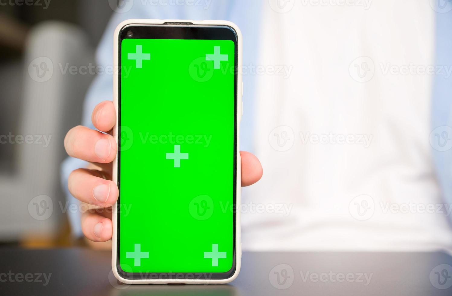 Closeup Mockup image of a man holding and showingsmartphone with green chroma screen photo