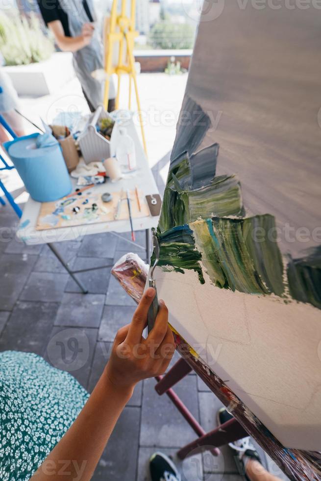 primer plano de la mano de la mujer aplicando pintura a un lienzo foto