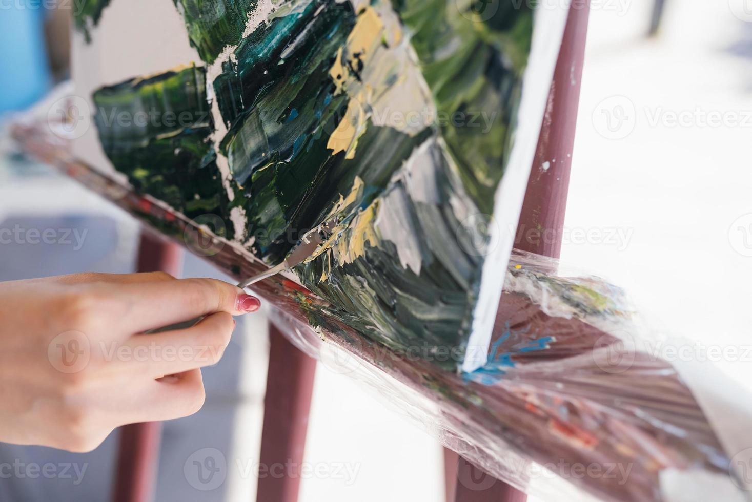 primer plano de la mano de una mujer aplicando pintura a un lienzo foto