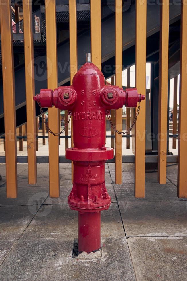 un rojo fuego boca de aguas con dos brazos en ambos lados dorado cerca antecedentes. estar tubo boca de aguas exterior. foto