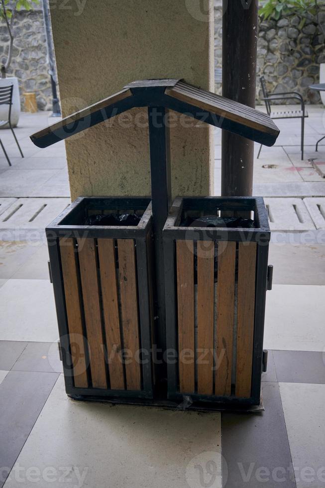Single rubbish bin, garbage and waste bin made of wooden material. A garbage collection tank in the corner of building. A clean container for household waste.  Wooden waste boxes or trash bin. photo