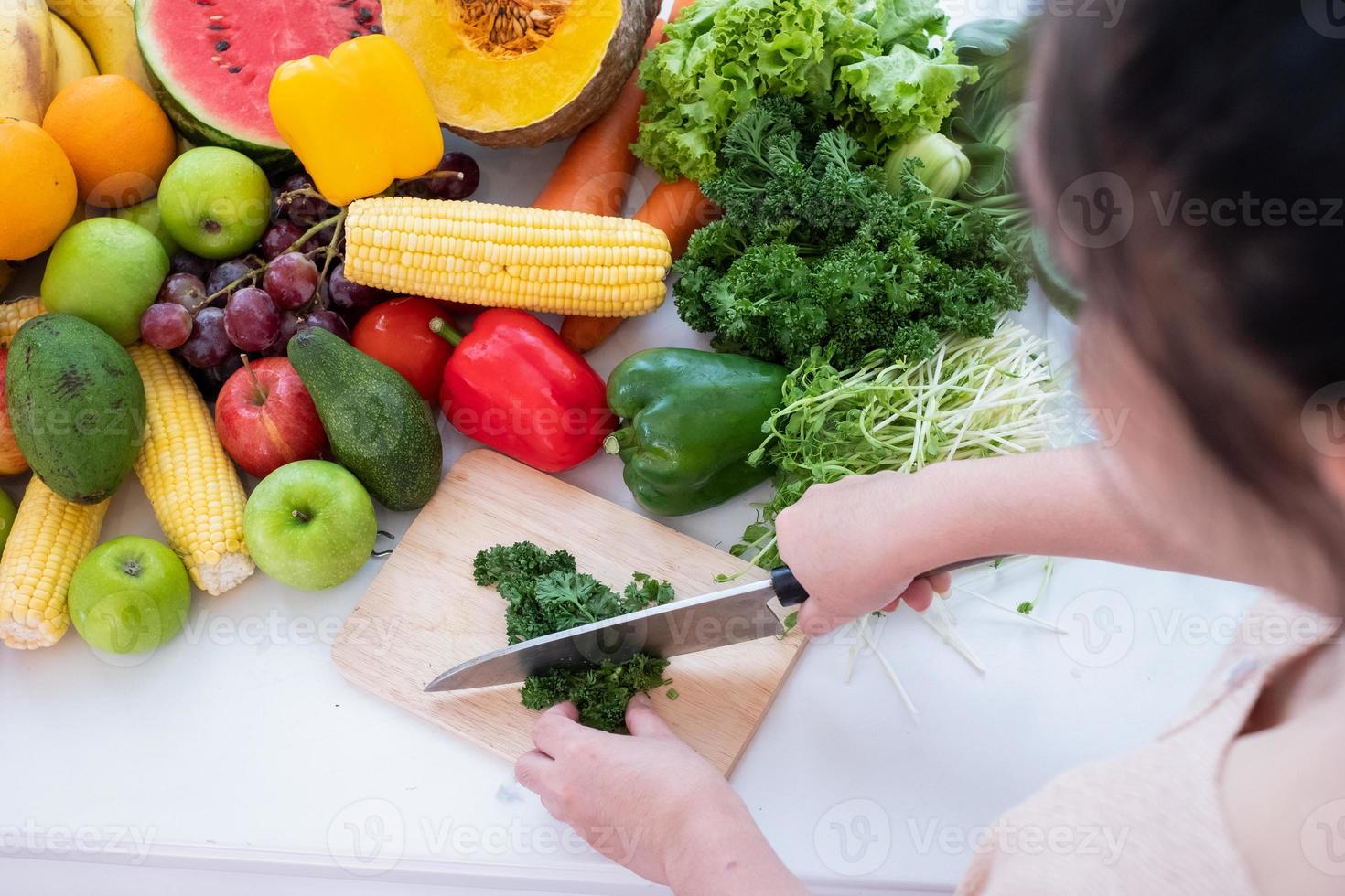 un de la persona manos son visible participación un cuchillo y el cortar vegetales en un corte tablero con Fruta el antecedentes es un blanco cortina foto