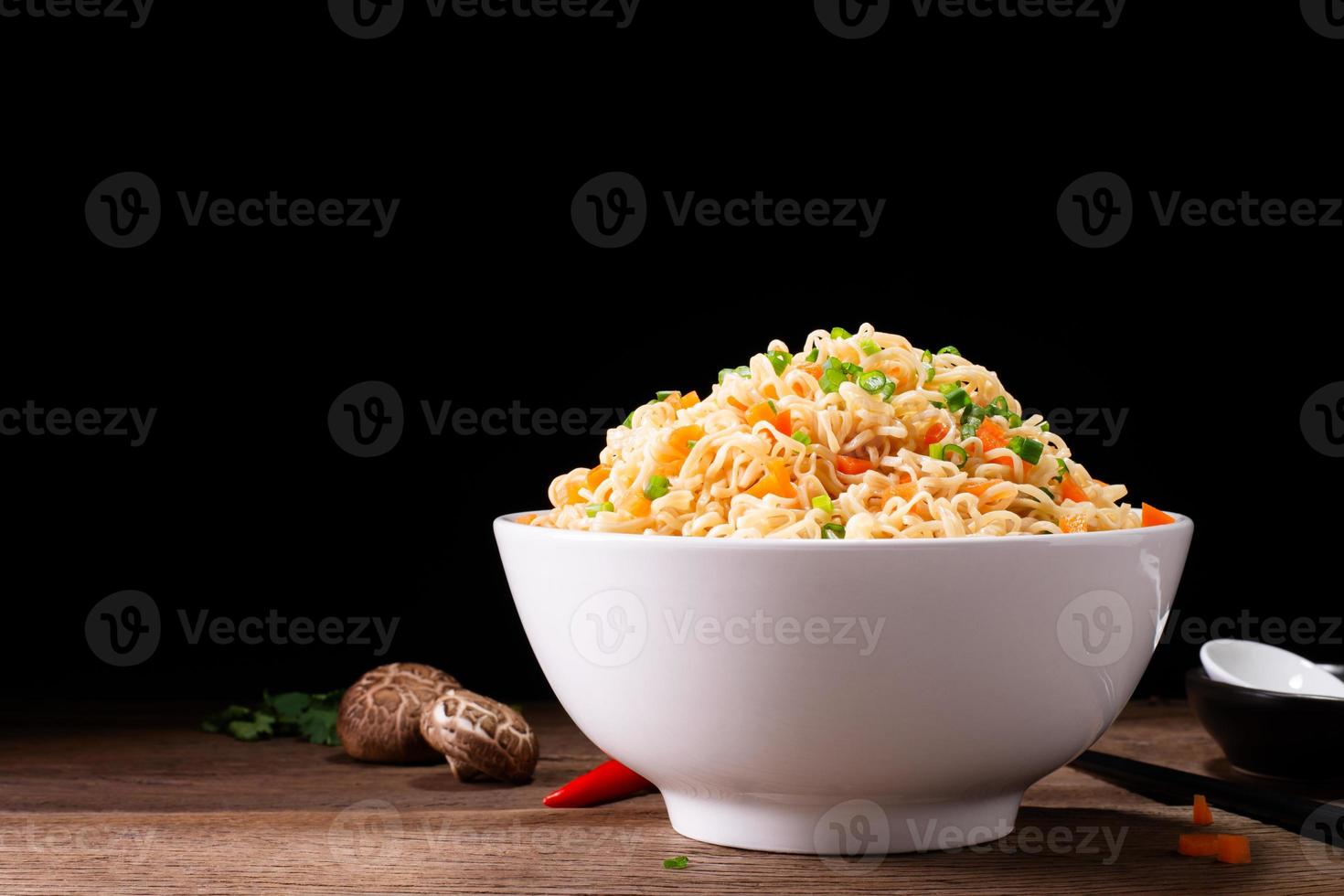 bowl of instant noodles or pasta. Delicious hot soup. Thai, Chinese, and Japanese food arranged on table isolated on black background. photo