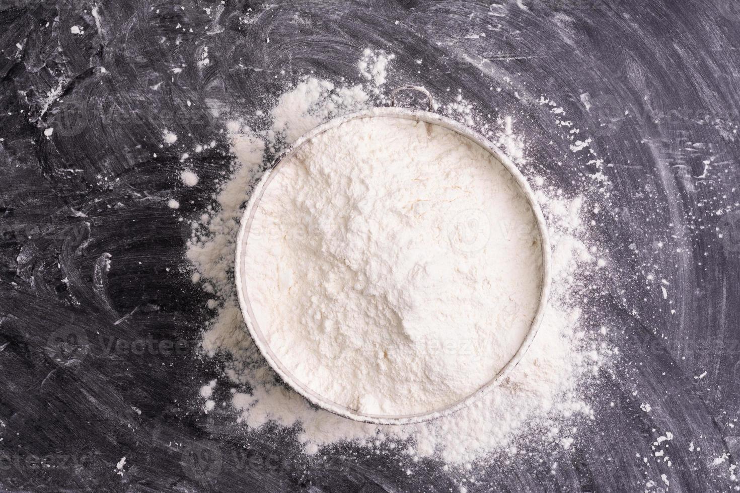 Flour in a bowl and wheat flour on table, black background In a rustic kitchen, top view photo