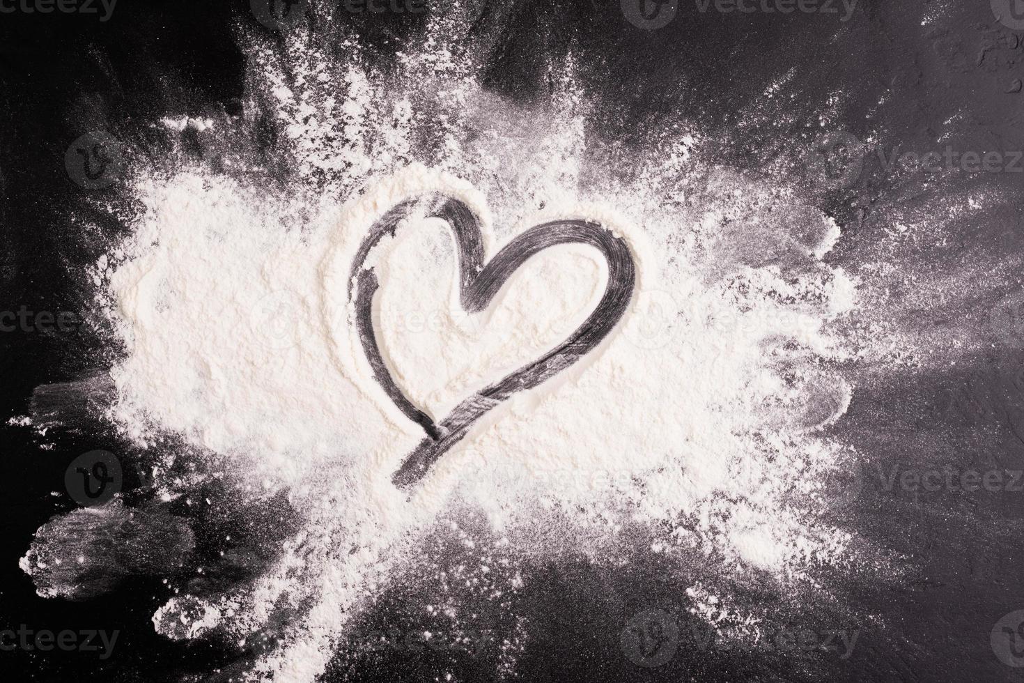 white podder bomb Scattering dough with heart shape on wooden table, black background photo