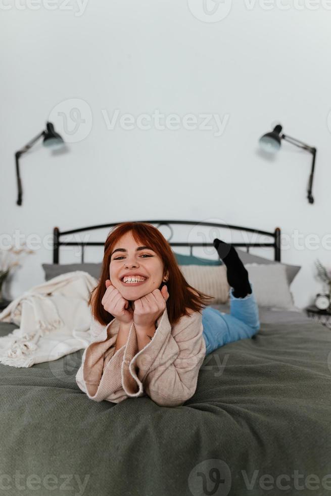 Cheerful young woman lying on the bed in the bedroom photo