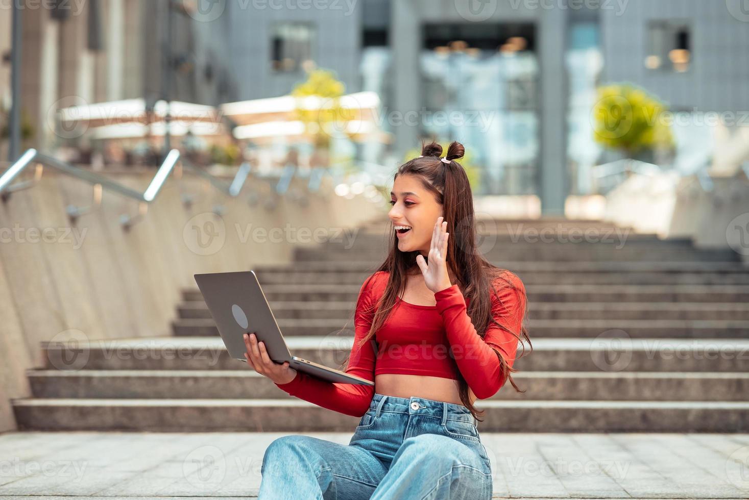 Woman on the street using laptop. Communicates via video link photo