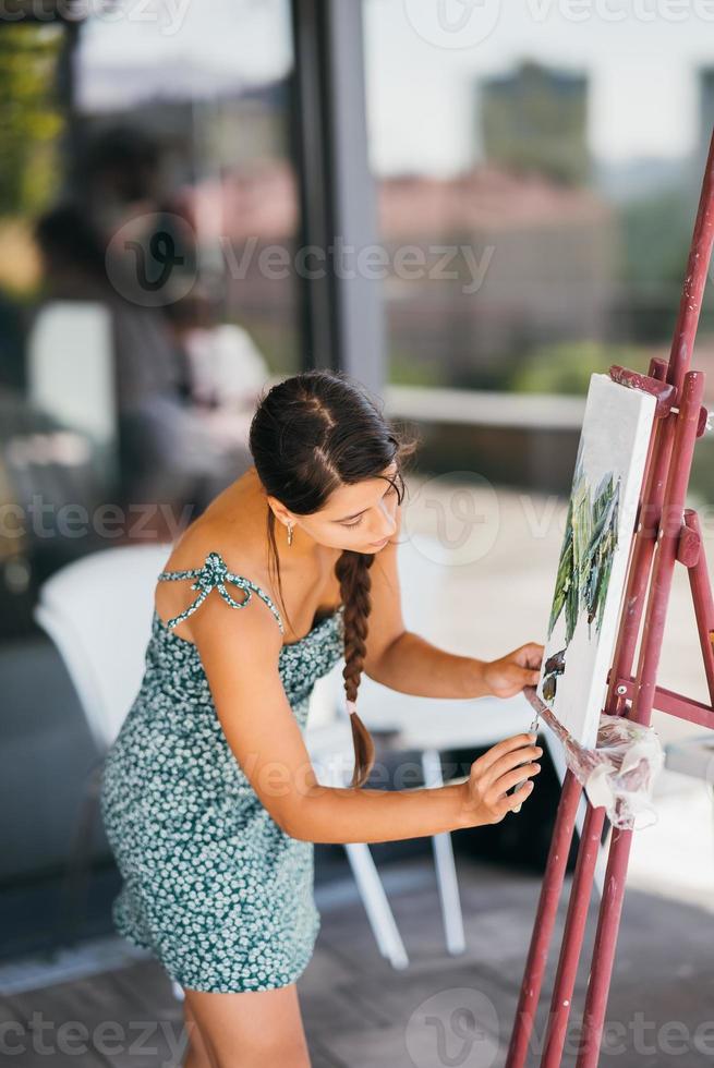 Young woman artist paints with a spatula on the canvas photo