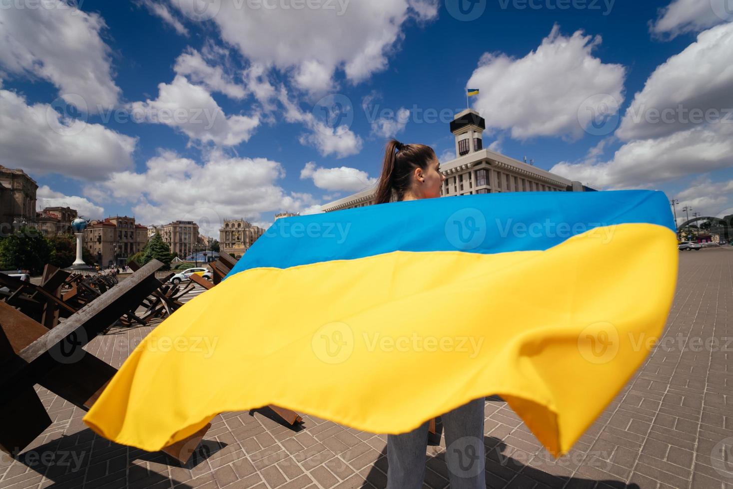 Young woman carries the flag of Ukraine fluttering behind her photo