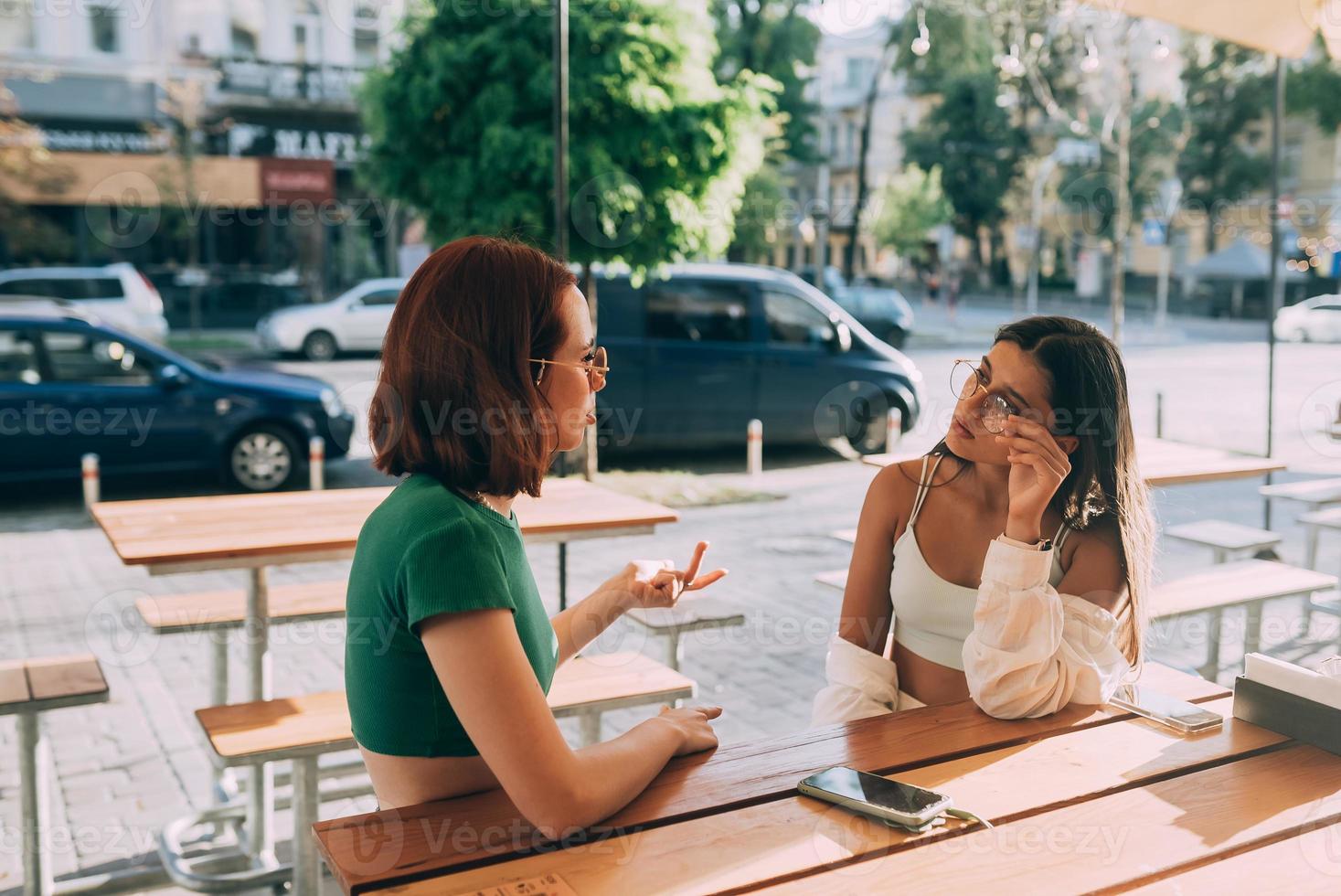 dos amigas bonitas hablando mientras están sentadas en un bar al aire libre foto