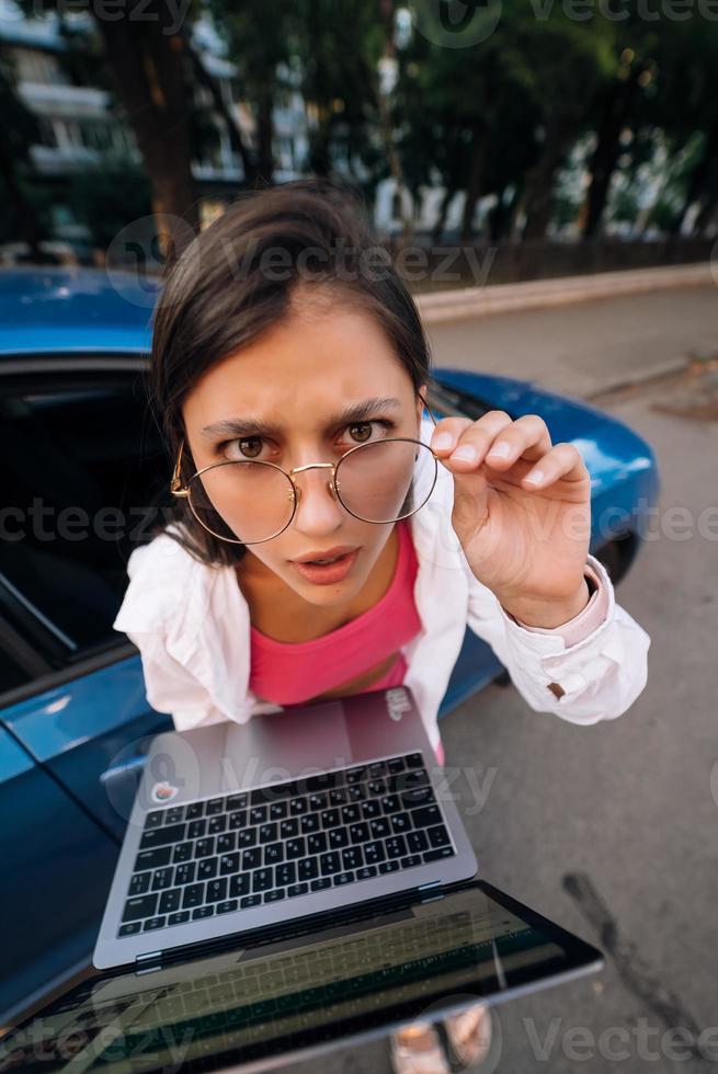Shocked young brunette hold in hands laptop on the street photo