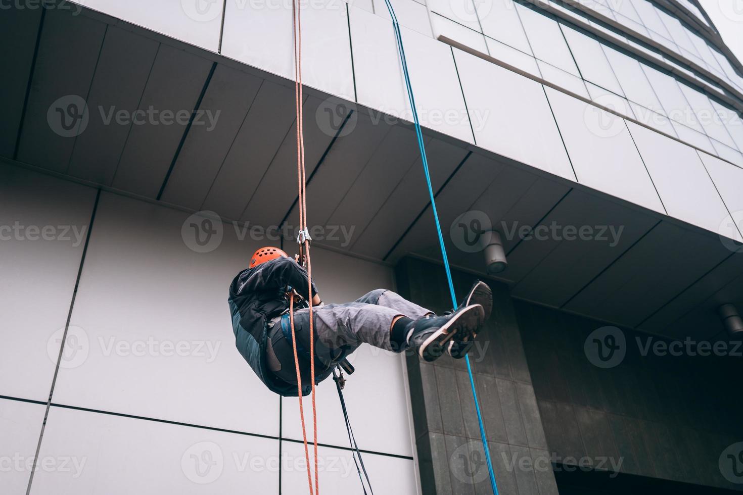 Industrial climber in uniform and helmet rises photo