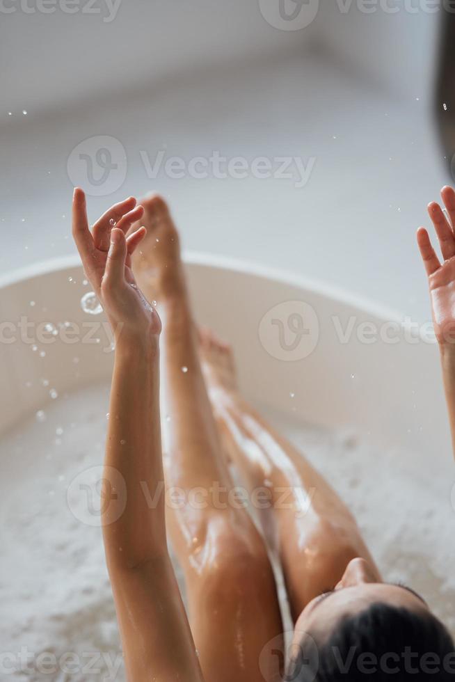 Pretty young woman taking bath at home back view photo