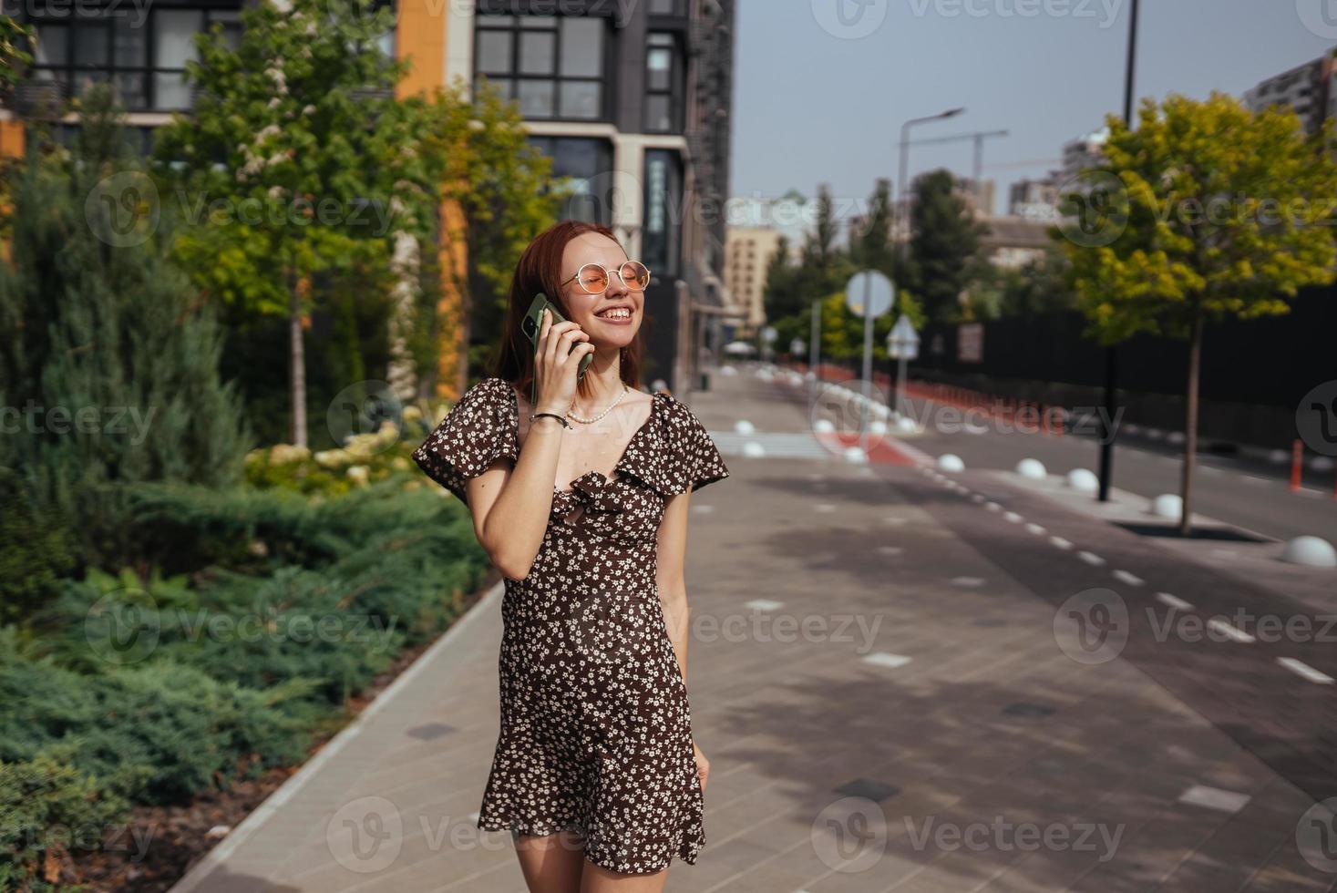 Cute girl talking on mobile phone on modern city background photo