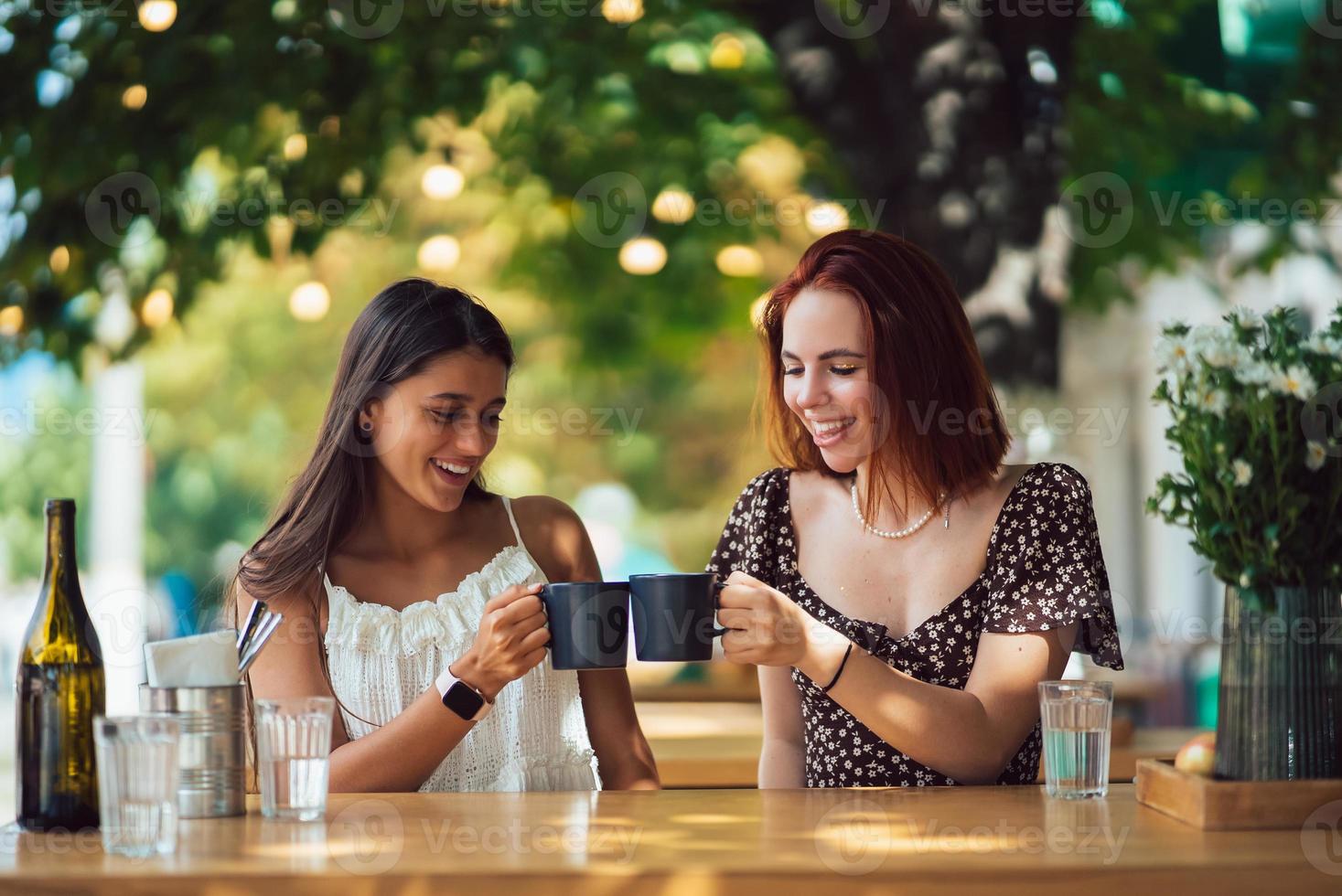 Two friends drinking coffee - women clinking with cups of coffee photo