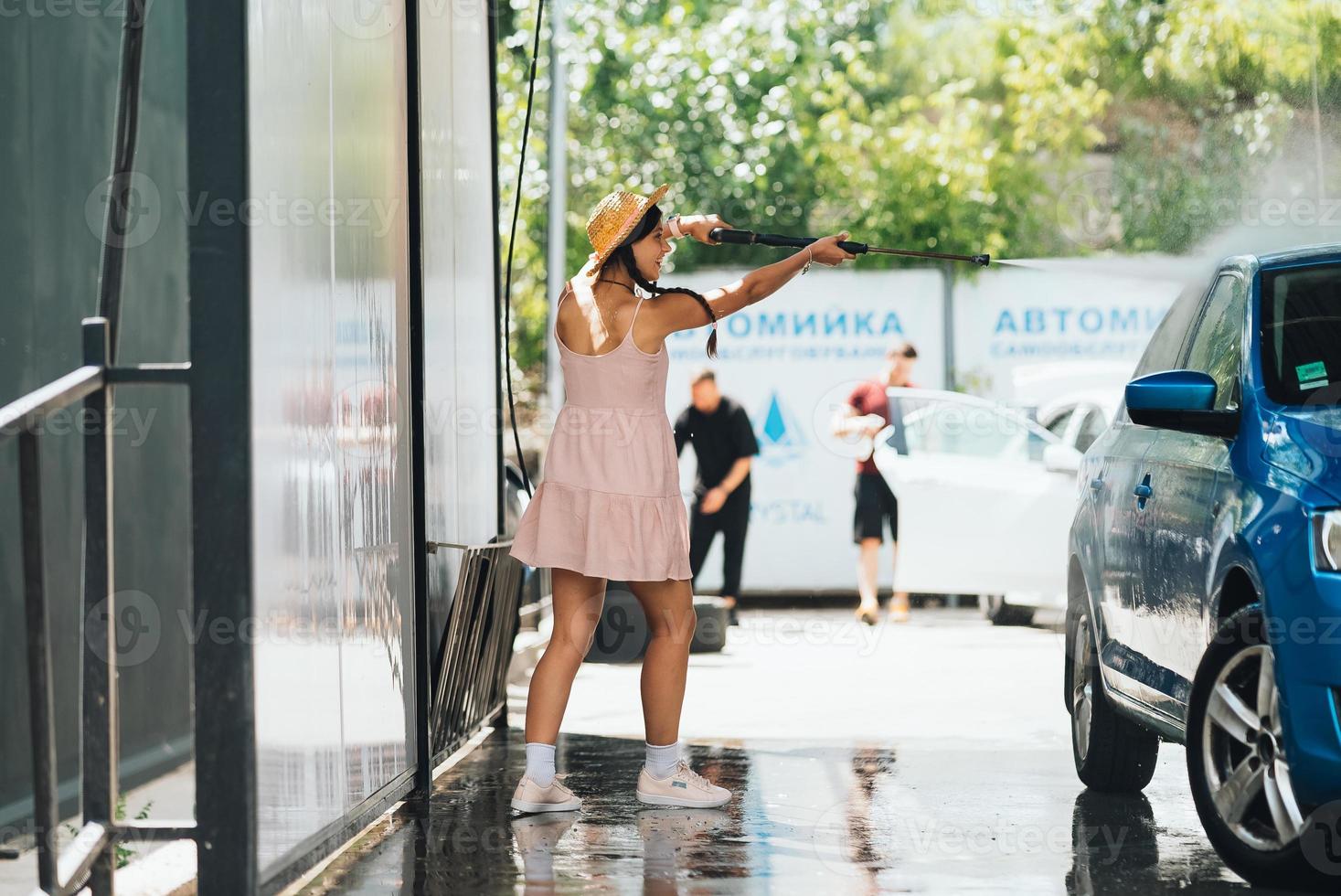 Brunette from a high-pressure hose washes the car photo