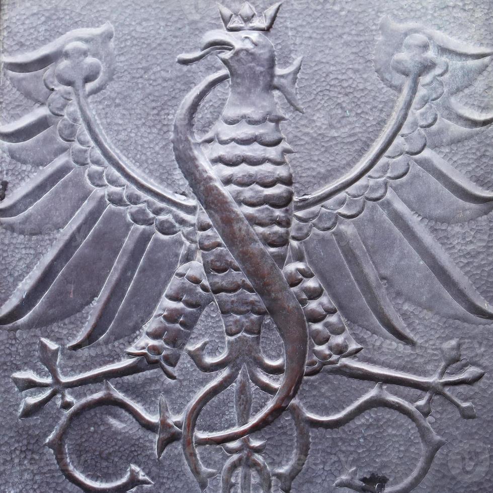 Close up fragment of medieval metal doors with eagle and snake, Poland. Part of antique old door photo