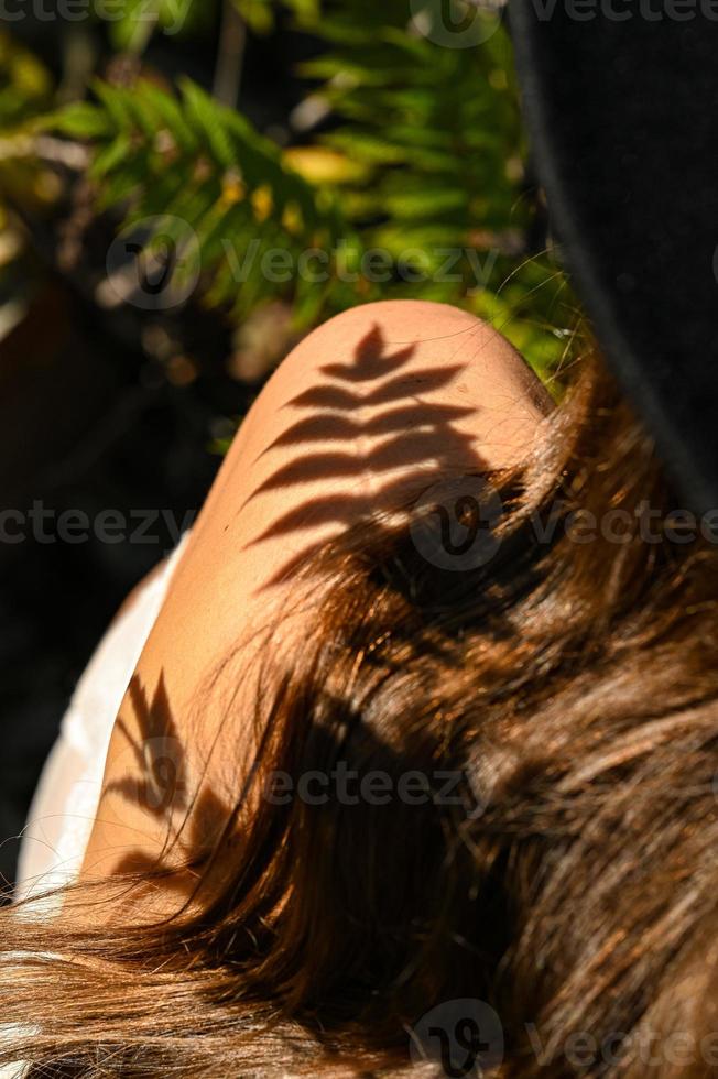 A girl with long hair is walking in the park. Beautiful warm sunset. A photo of a pretty young woman smiling at the wind in long curly brunette hair.