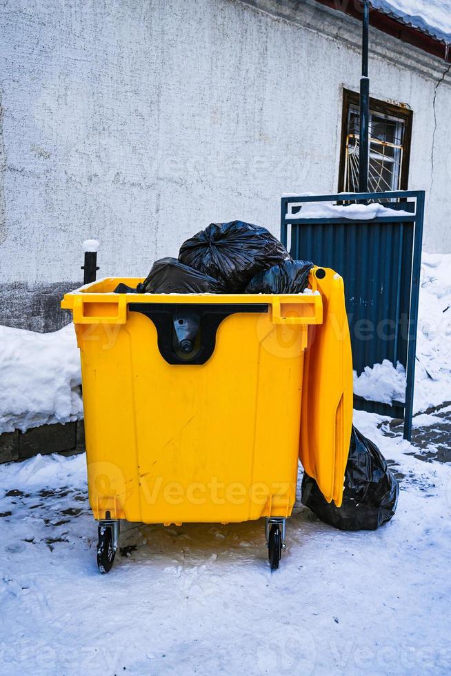 Yellow plastic dumpster with black bags photo