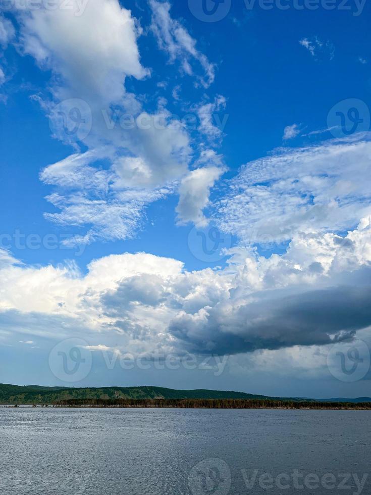 arboles y blanco nubes por el río con azul agua. río paisaje. reflexión de el cielo en el río. foto