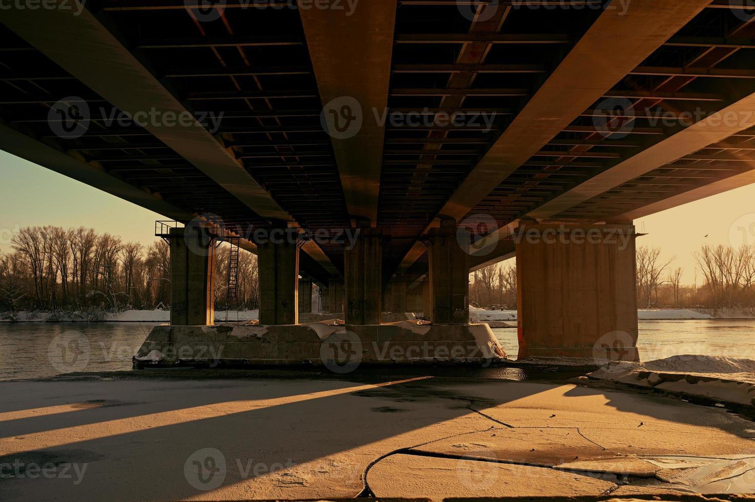 An asphalt road under a steel bridge structure in the city. Night city scene with car lanes. photo