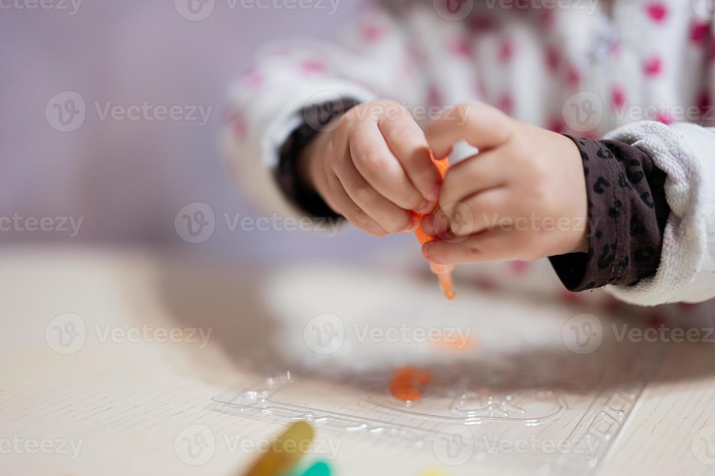 Close up hands of baby girl decorating art with glitter decor tube of paint. photo