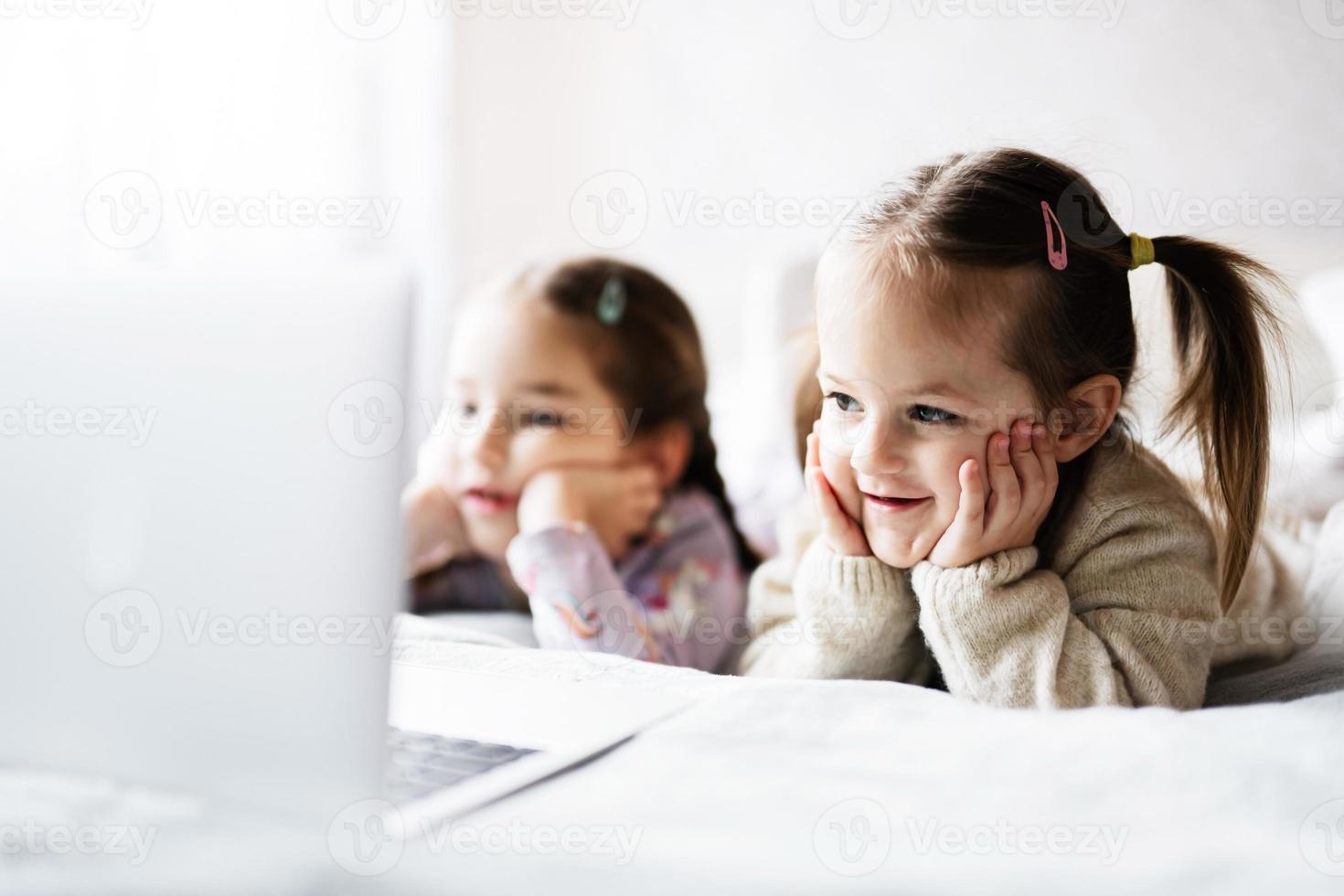 Two girls sisters watching on laptop. Technology and home concept. photo