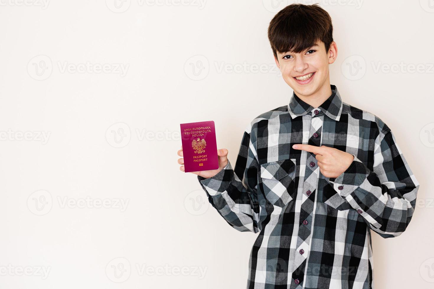 joven adolescente chico participación Polonia pasaporte mirando positivo y contento en pie y sonriente con un confidente sonrisa en contra blanco antecedentes. foto