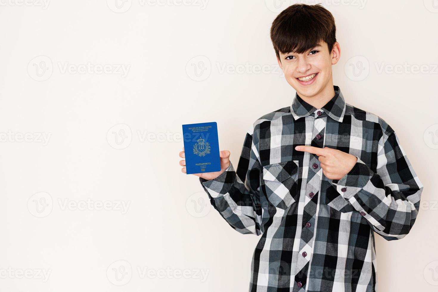 joven adolescente chico participación san marino pasaporte mirando positivo y contento en pie y sonriente con un confidente sonrisa en contra blanco antecedentes. foto