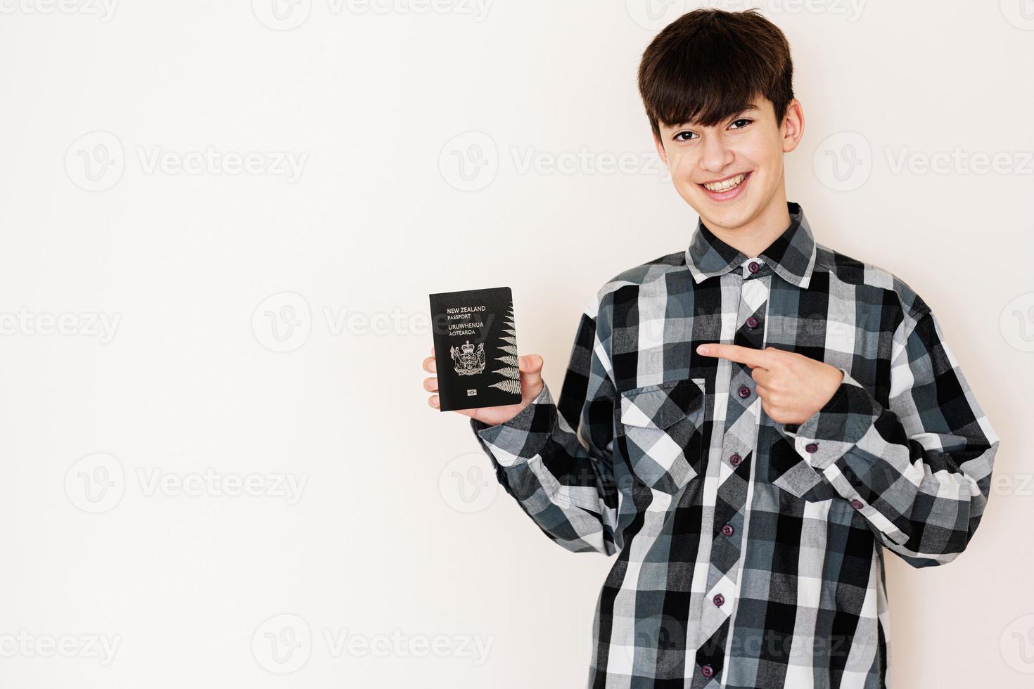 Young teenager boy holding New Zealand passport looking positive and happy standing and smiling with a confident smile against white background. photo