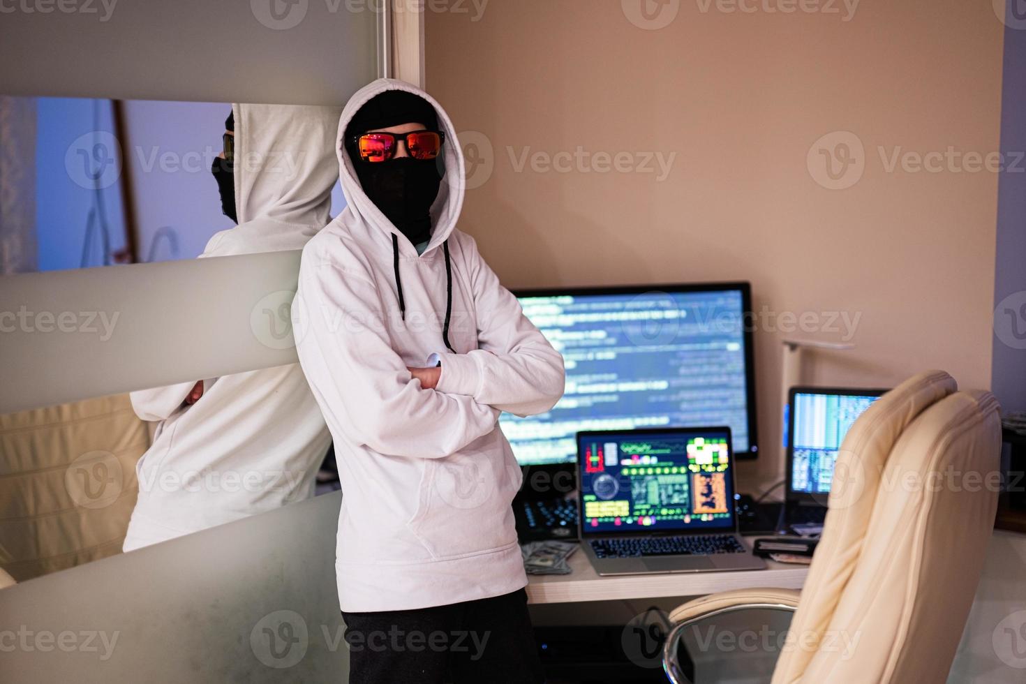 Boy hacker. Internet theft . Man wearing a balaclava behind a laptop. photo