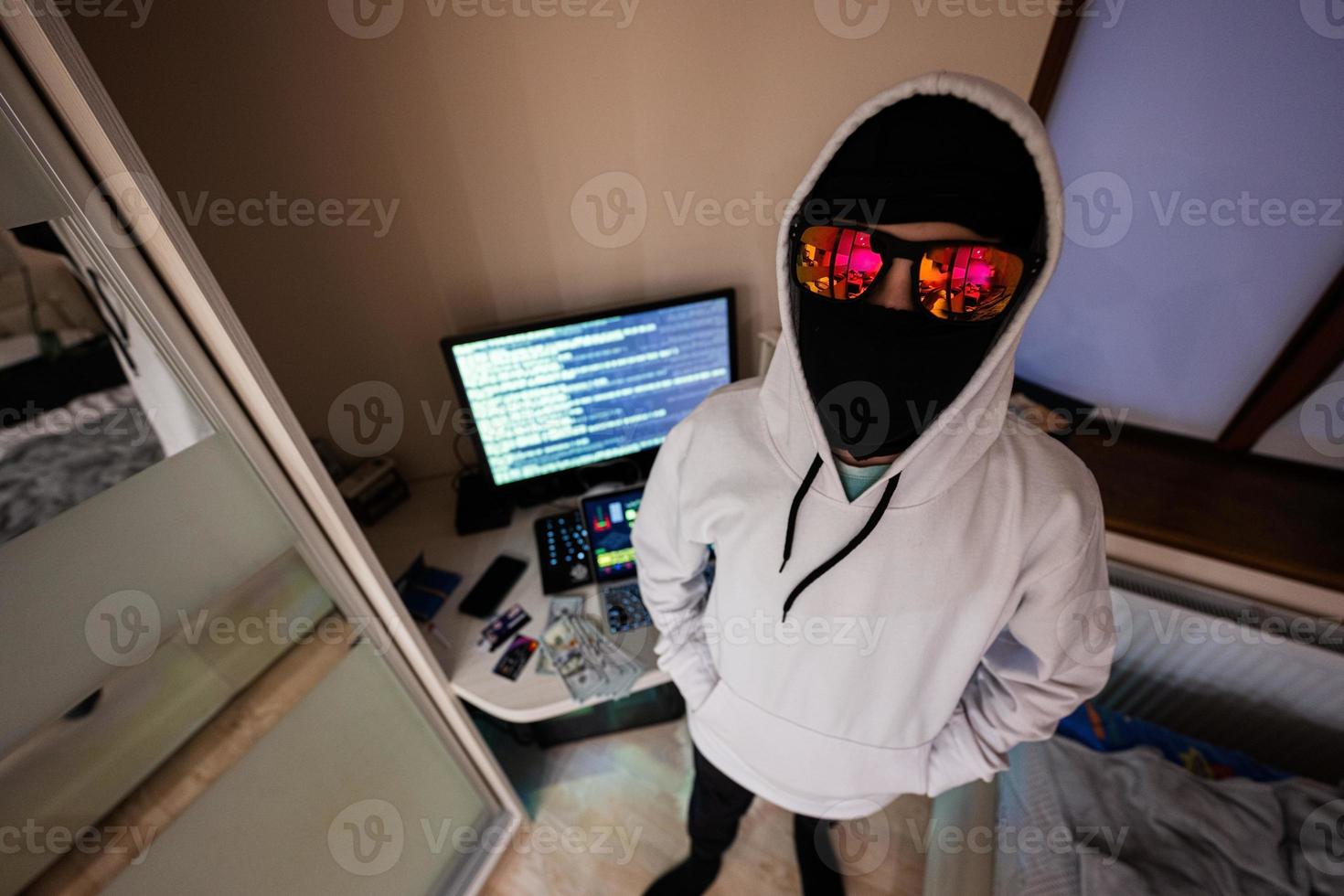 Boy hacker. Internet theft . Man wearing a balaclava behind a laptop. photo
