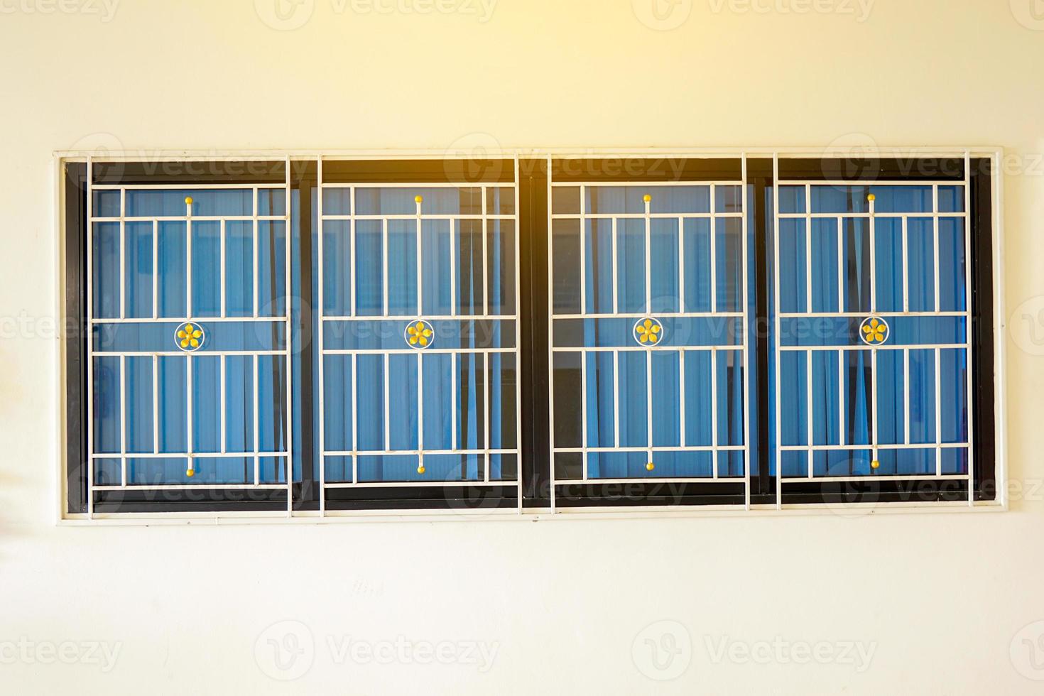 Aluminum windows, glass panes, inside decorated with blue curtains. The outside is fitted with wrought iron for safety. Soft and selective focus photo