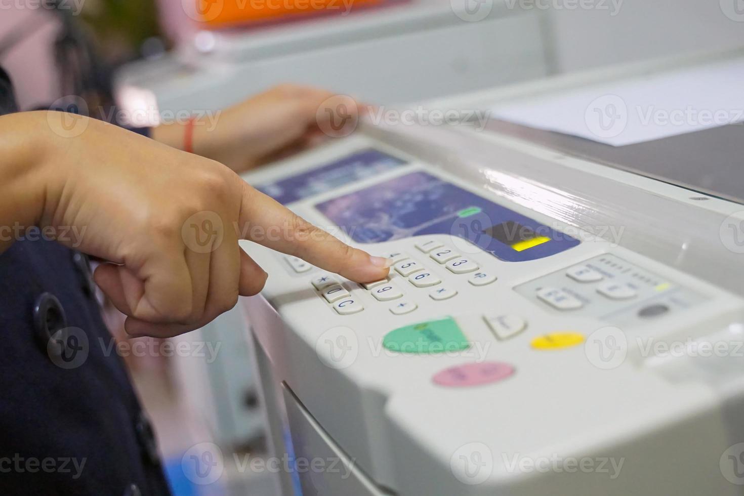 office worker Pressing a number button on the copier to specify the number of documents to be copied. soft and selective focus. photo